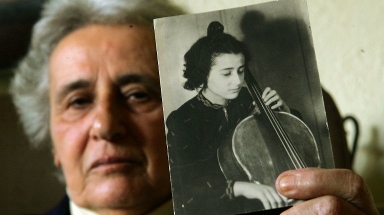 A sobrevivente do Holocausto Anita Lasker-Wallfisch, em 2005, com uma foto em que toca violoncelo antes da Segunda Guerra Mundial
