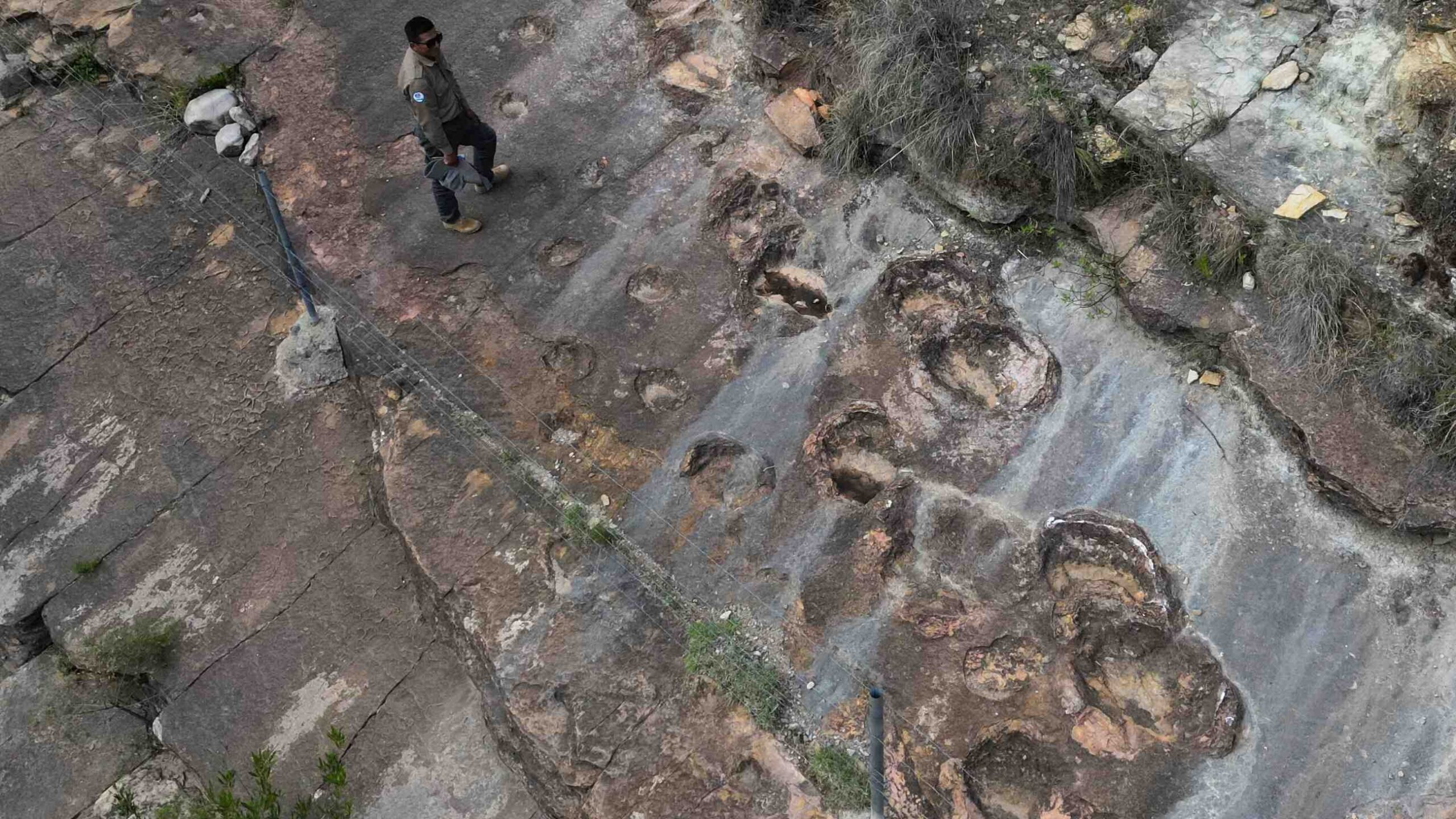 O guarda-parque José Vallejos ao lado de pegadas de dinossauros petrificadas em Carreras Pampa, no Parque Nacional Torotoro, ao norte de Potosí, na Bolívia